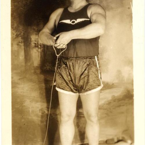 [Police officer and olympic champion James E. McEachern posing with 56 lb. weight and hammer throw]