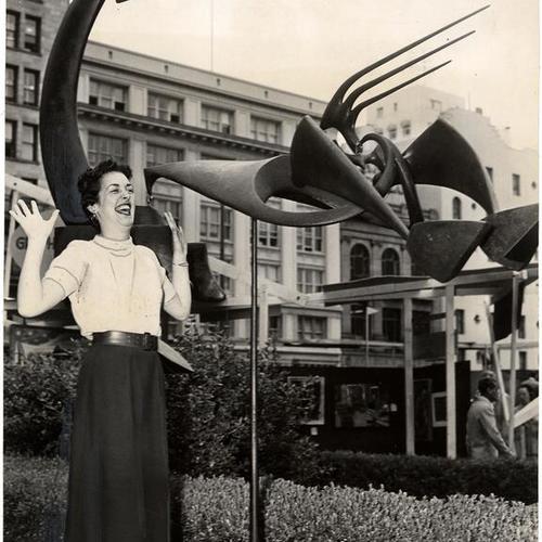 [Joan Millak standing next to Robert B. Howard's mobile, 'Excelsior,' at Union Square in the Seventh Annual Art Festival]