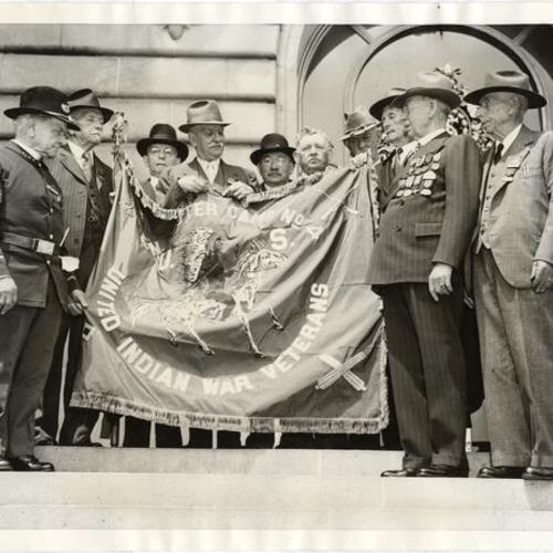 [Veterans of Indian Wars displaying new flag presented to them during ceremony at the War Memorial Opera House]