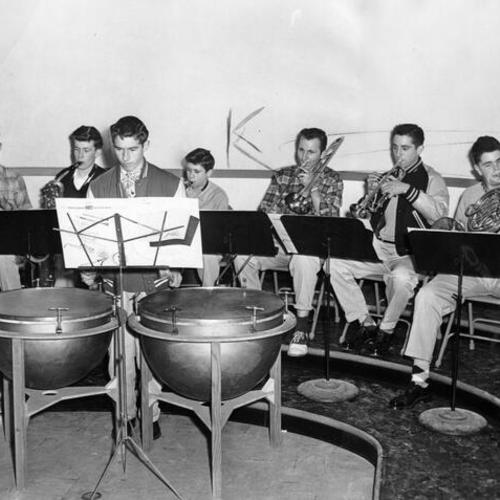 [Several members of the Riordan High School band practicing in rehearsal room]
