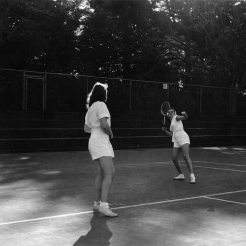 [Two women playing tennis in Golden Gate Park]