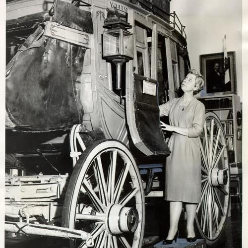 [Irene Simpson standing next to an early Wells Fargo stagecoach]