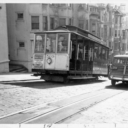 [Powell Street cable car ascending up a hill]