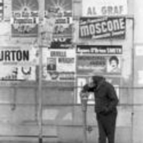 [Election campaign posters cover wall behind a man observing demolition on the 700 block of Howard,
