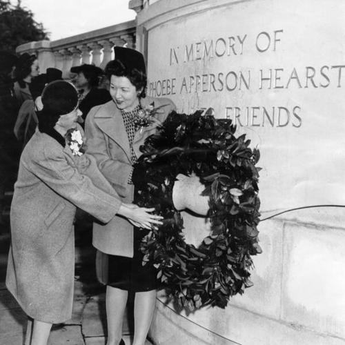 [Mrs. Dean Parker and Mrs. George H. Bowman placing a wreath on the monument to Phoebe Apperson Hearst in Golden Gate Park]