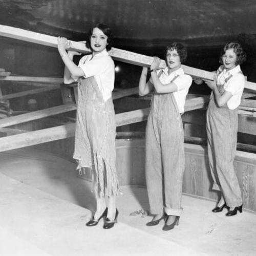 [Viola Allen, Mildred Davis, and Mary Bowers pose as construction workers in a publicity photo during the construction of the Fox theater]