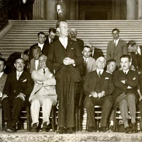[Smith Kingsford speaking in front of a crowd in the rotunda of City Hall]