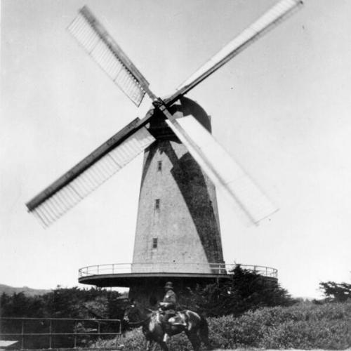 [Mounted policeman in front of windmill in Golden Gate Park]