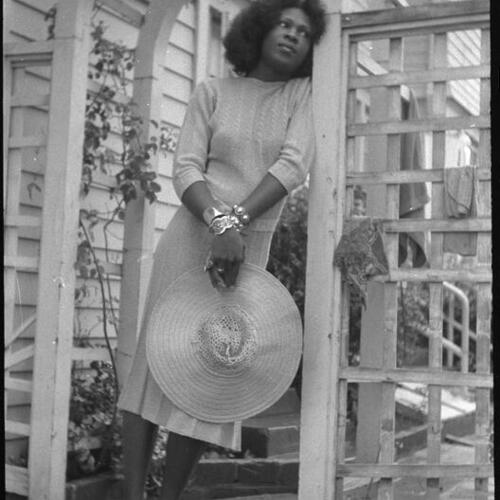 Sylvester holding hat standing under arbor outdoors at Peter Mintun's house, Mountain View