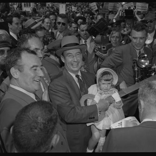 Adlai Stevenson holding child at campaign rally