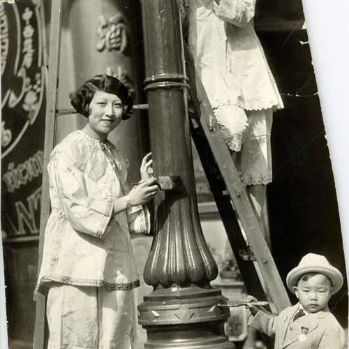 [Lina Leong painting a lamp post with two fellow artists]