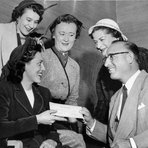 [Joe Giacometti, of Sears, Roebuck & Company, handing over a check to members of the Cow Hollow Women's Club as a donation to the club's children's playground activities]