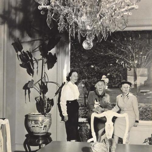 [Mrs. Francis V. Keesling Jr., Mrs. Ferdinand Smith and Mrs. Harold Boucher posing for a picture in the home of Mr. and Mrs. Ferdinand Smith at 825 Francisco Street]