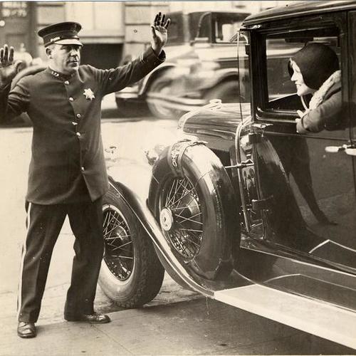 [Officer J. F. McGreen talking with Mrs. Chas H. Harvey, seated at the steering wheel]