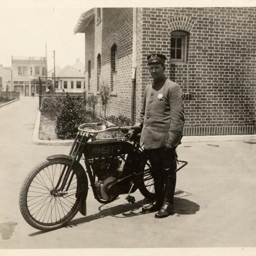 [Police officer standing next to a SFPD bike in front of the Richmond Police Station]
