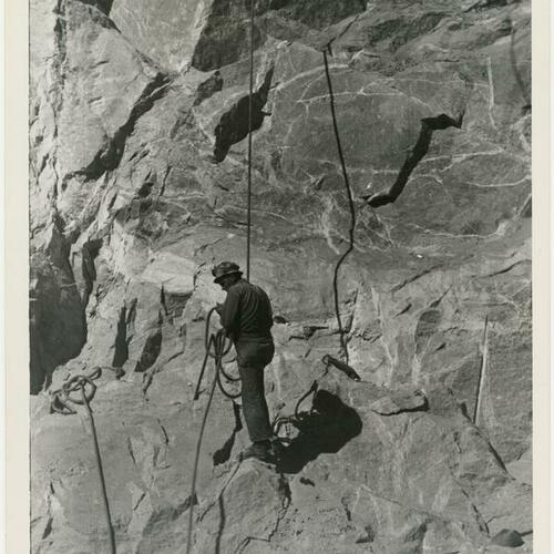 Worker rappelling down rock face during O’Shaughnessy Dam construction