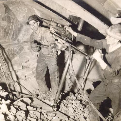 [Anthony Molles and Henry Jorgensen, San Francisco-Oakland Bay Bridge workmen, digging inside Yerba Buena Island tunnel]