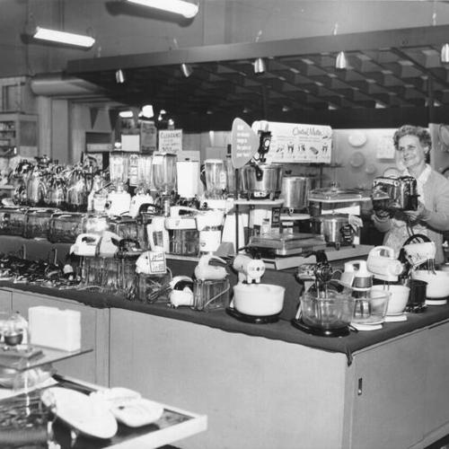 [Unidentified woman holding a toaster in the kitchen appliance department at the Crystal Palace Market]