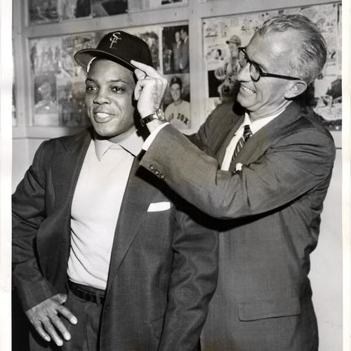 [Manager Bill Rigney, right, placing a San Francisco Giants cap on Willie Mays]