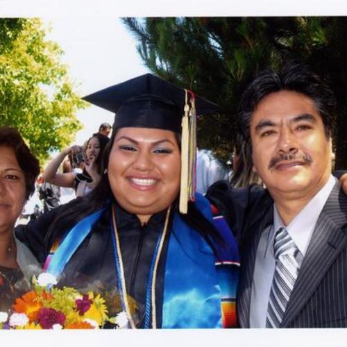 [A woman with her parents on graduation day from UC Irvine]