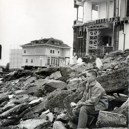 [John Gallagher sitting in front of the Moffitt mansion as it sits in front of the Marina seawall before it is carried out to sea on a barge]