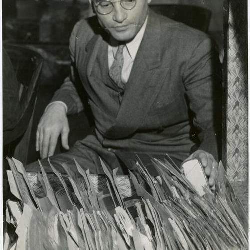 [Albert Del Guercio, chief government counsel in Bridges hearing thumbs over his stock of note and exhibits concerning the Harry Bridges deportation case]