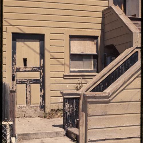 Withered building exterior with staircase and broken window
