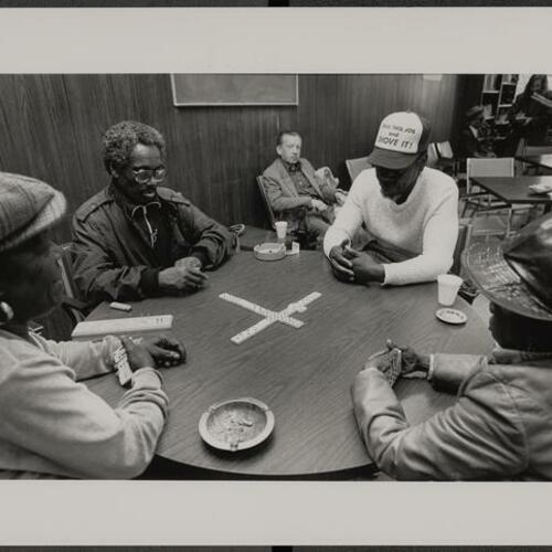 People at table playing dominos at North of Market Senior Sobriety Club at 291 Eddy Street