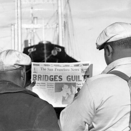 [In the shadow of the ship they're working on San Francisco's waterfront, two longshoremen study a copy of The News reporting the verdict against Harry Bridges, top man of the longshore union]