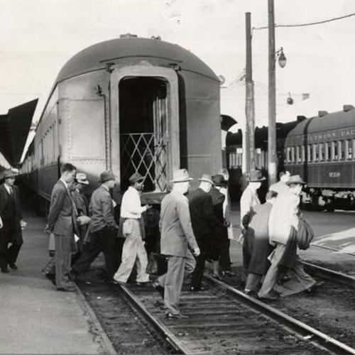 [Commuters crossing a railroad track at Southern Pacific Depot]