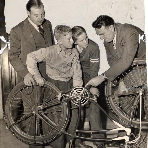 [Sergeant John Meehan (right) helping two youngsters with their bicycle as Officer William Valentine (left) looks on]