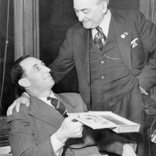 [Harry Bridges (seated) is shown as he received congratulatory cigars from Capt. Charles Huston, 