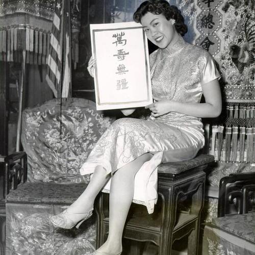 [Queen of the Chinese New Year festival, Karen Lim, holding a card that reads "Much Prosperity"]