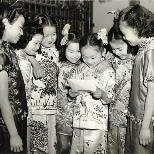 [Group of young Chinese girls looking over bonds they purchased]