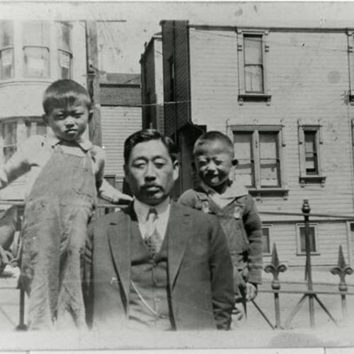 [Two brothers with uncle in front of houses on Octavia Street]