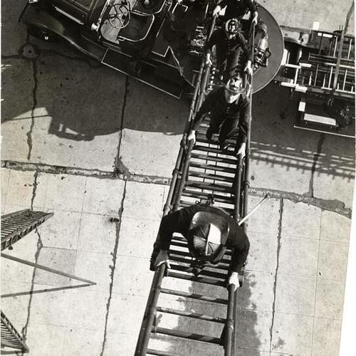 [Firemen from Truck 13 scaling an aerial ladder during a practice session]