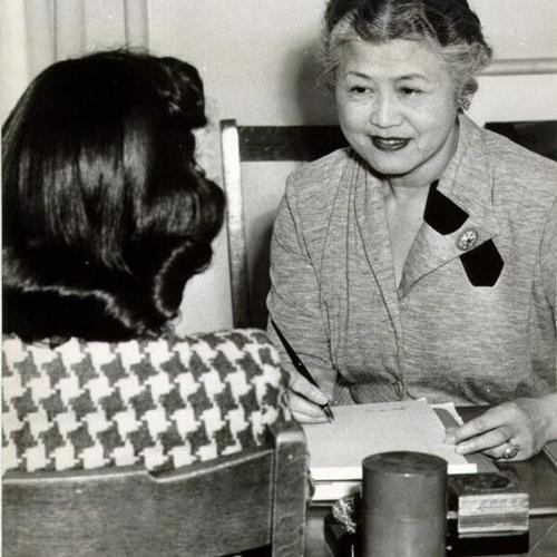 [Rose Chew interviewing a young Chinese immigrant woman at the International Institute, a Community Chest agency]