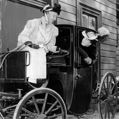 [Mrs. Herbert Schick and Mrs. Clyde McDowell riding on a horse drawn vehicle]