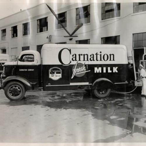 [Employees of Carnation Company stocking items in a company truck]