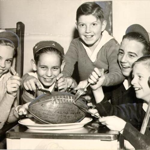 [Group of children from the Shriners' Hospital for Crippled Children posing with a football signed by players in the East-West football game]