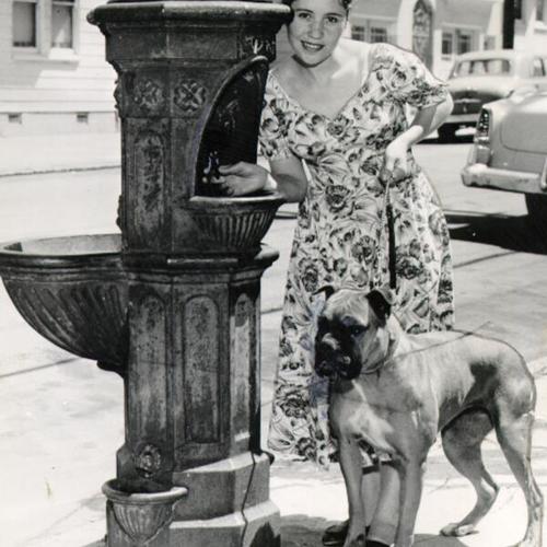 [Mrs. Amada Rivera, posing with her dog, in front of an 82-year-old fountain in the Mission district]