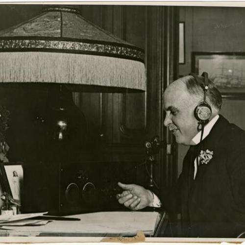 [Mayor James Rolph, Jr. listens to a radio]