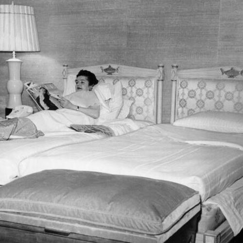 [Unidentified woman reading in bed of suite used by Khrushchev at the Mark Hopkins Hotel]
