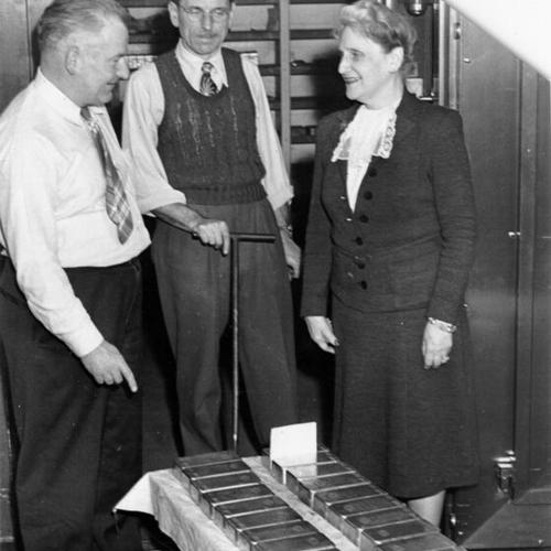 [Joseph A. Heyfrom, Herman R. Klauser and Mrs. Nellie Taylor Ross inspecting gold bars at the U. S. Mint in San Francisco]
