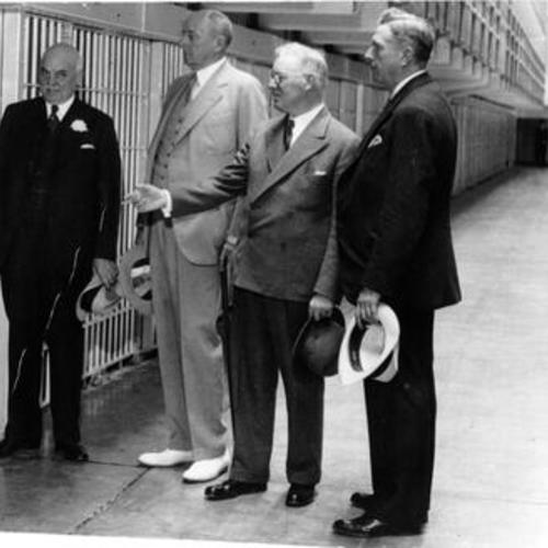 [San Francisco Mayor Angelo Rossi, United States Attorney General Homer S. Cummings, Warden James A. Johnston and San Francisco Chief of Police Quinn view cells at Alcatraz Island prison]