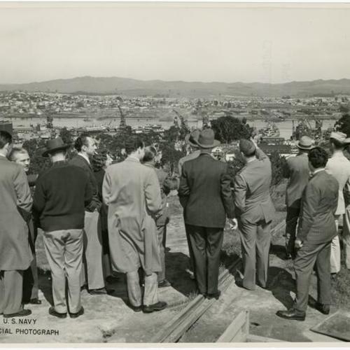 [Members of the press looking down on Hunters Point from a nearby hilltop]