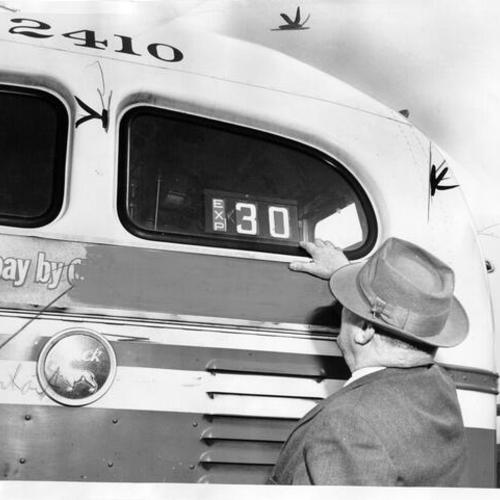[Victor Peterson examines rear number sign of Municipal Railways trackless trolley car number 2410]
