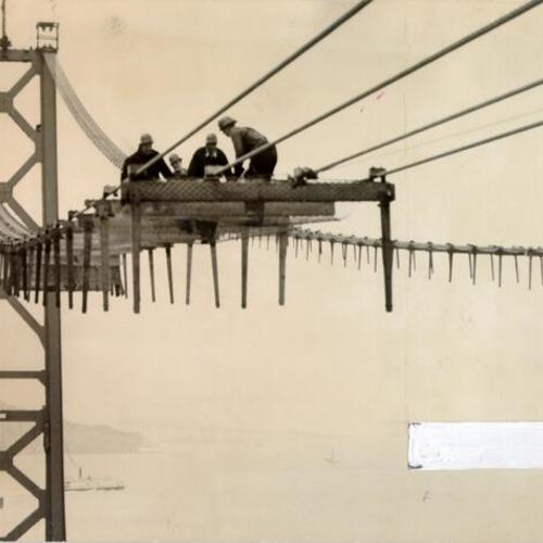 [Men working on a catwalk during construction of the San Francisco-Oakland Bay Bridge]