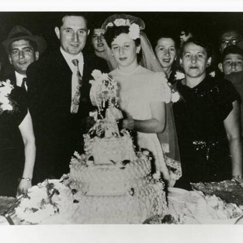 [Marion's wedding and her wedding cake surrounded by friends and family]