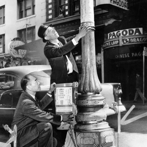 [Col. John S. Young and Bernard M. Croty installing an experimental litter basket on Grant Avenue in Chinatown]